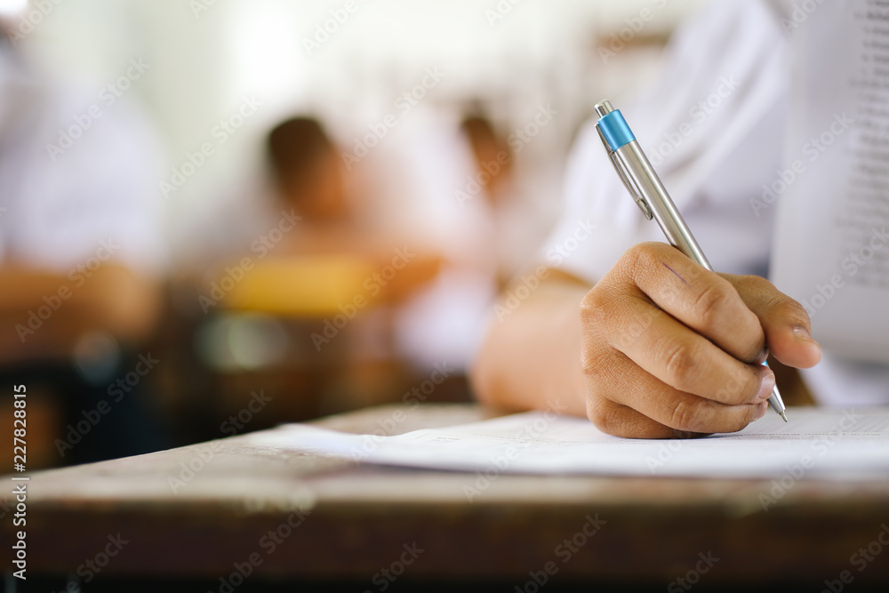 参加课程考试的制服学生的书写手特写。