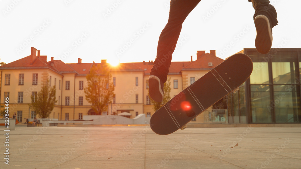 特写：日落时分，年轻的滑冰运动员在城市公园滑冰时上演了一个酷炫的动作。