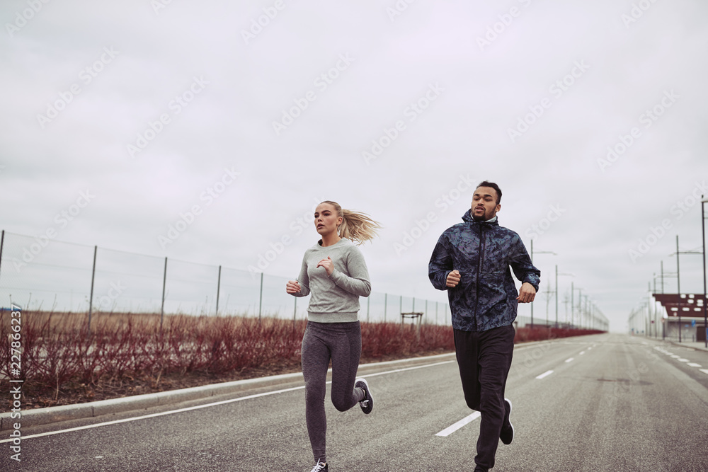 在乡间小路上奔跑的多元化年轻夫妇