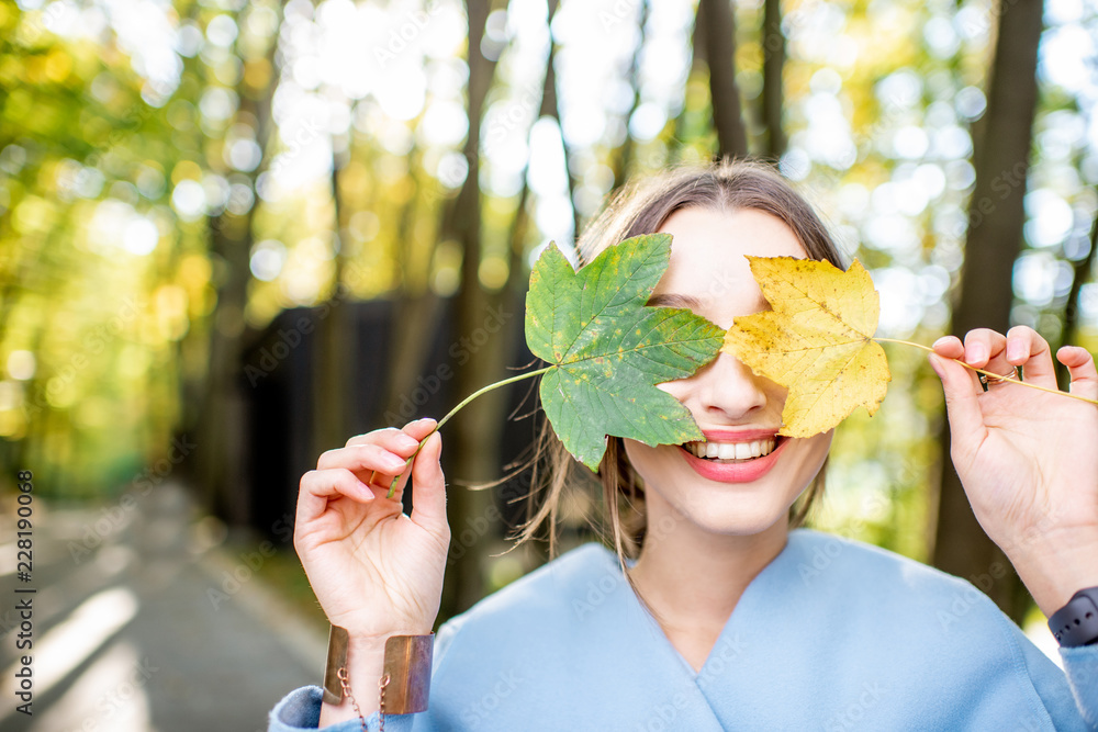 秋天森林里，一位美丽的女人在户外长着五颜六色的叶子的特写肖像