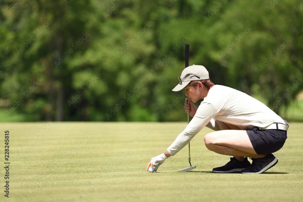 女高尔夫球手将高尔夫球放在草地上的检查线