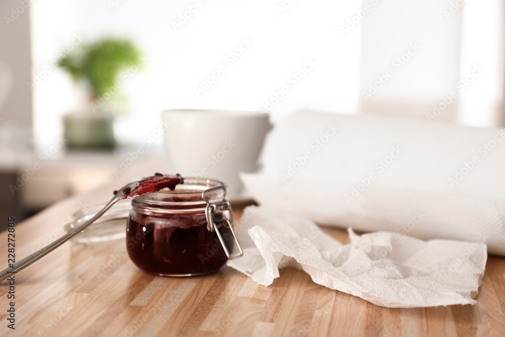厨房桌子上一卷纸巾和一罐果酱