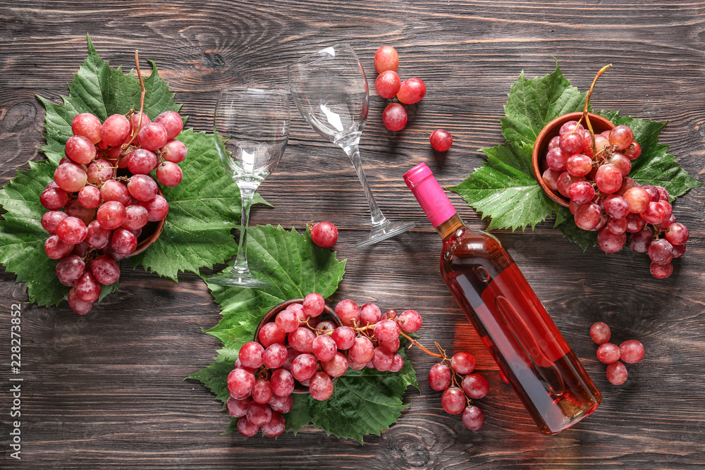 木桌上的一瓶红酒、玻璃杯和成熟的葡萄