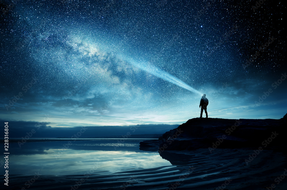 一个人站在那里看着银河系升上夜空。照片合成