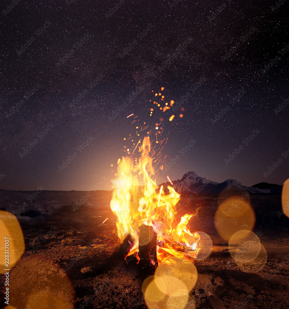 晚上在温暖的篝火旁观看星星。照片合成。