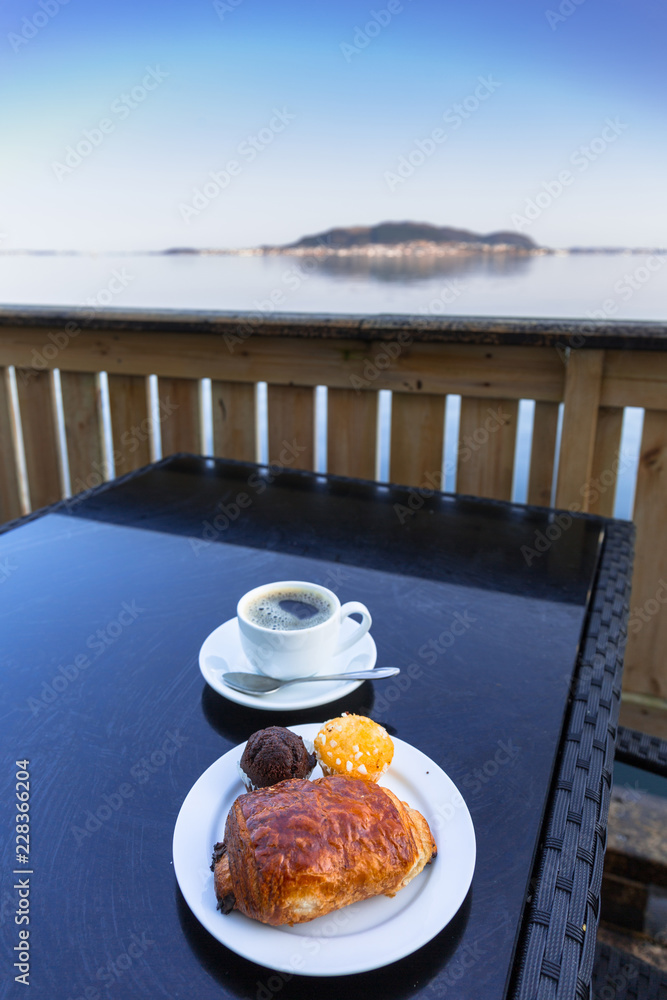 Coffee cup and croissant on the table by the sea