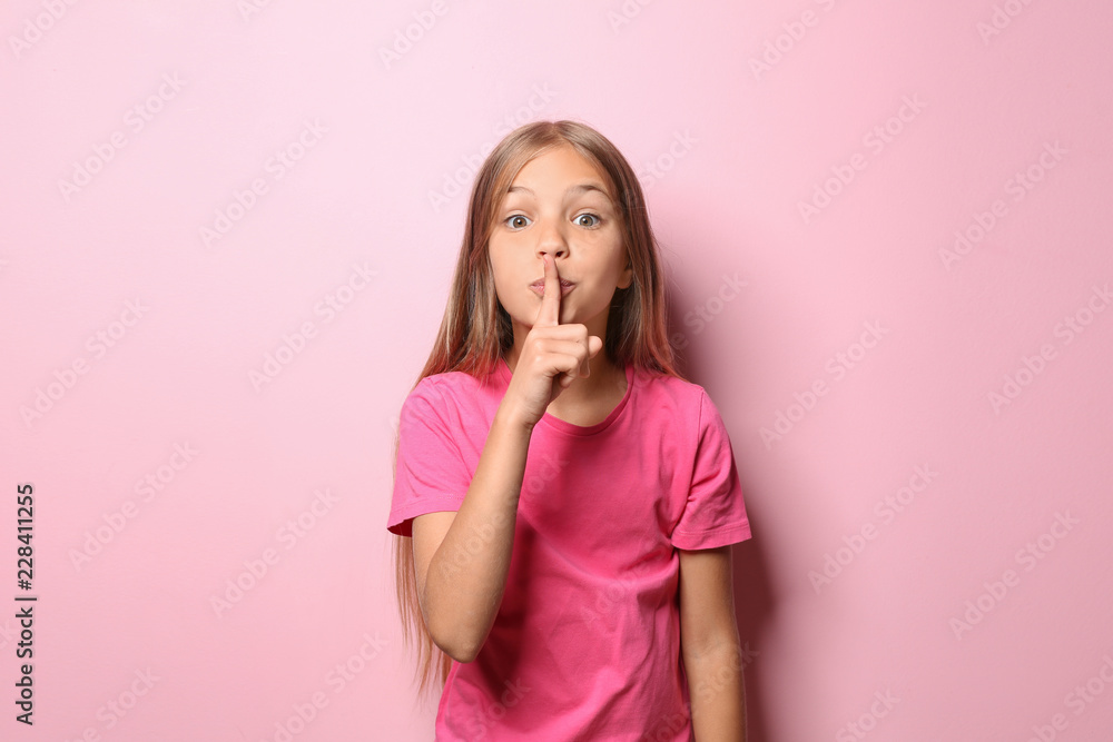 穿着t恤的小女孩在彩色背景上做出沉默的手势