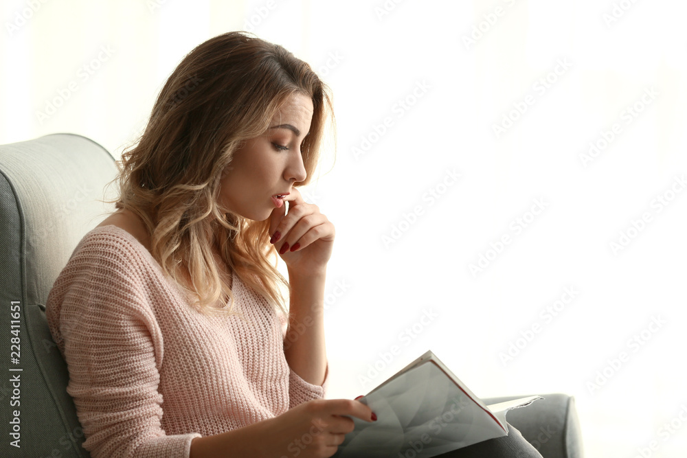 美丽年轻女子在家阅读杂志的肖像