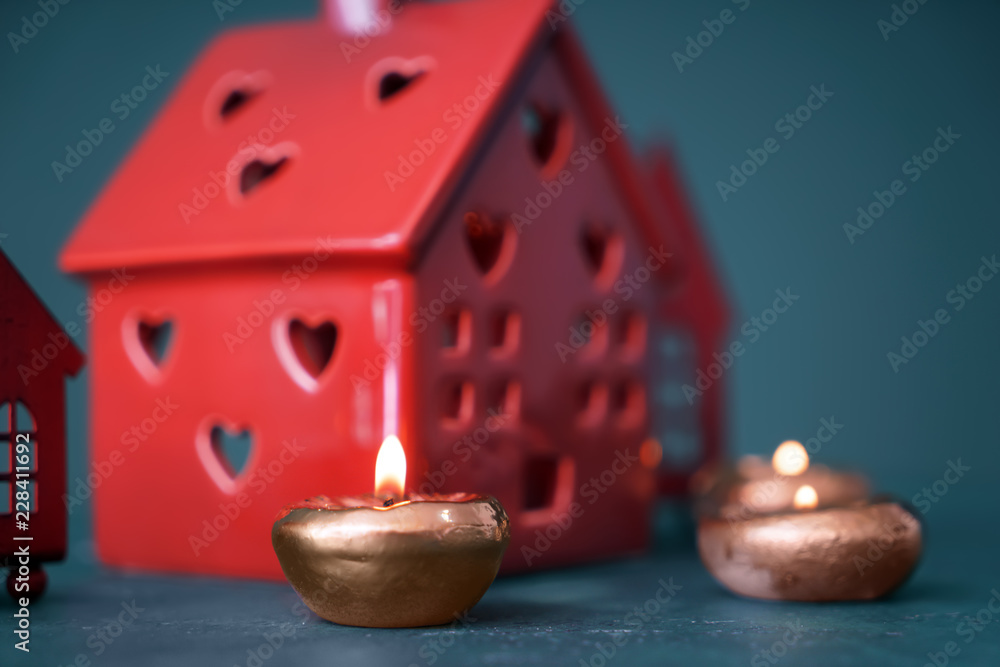 漂亮的燃烧蜡烛，彩色桌子上有房子形状的支架