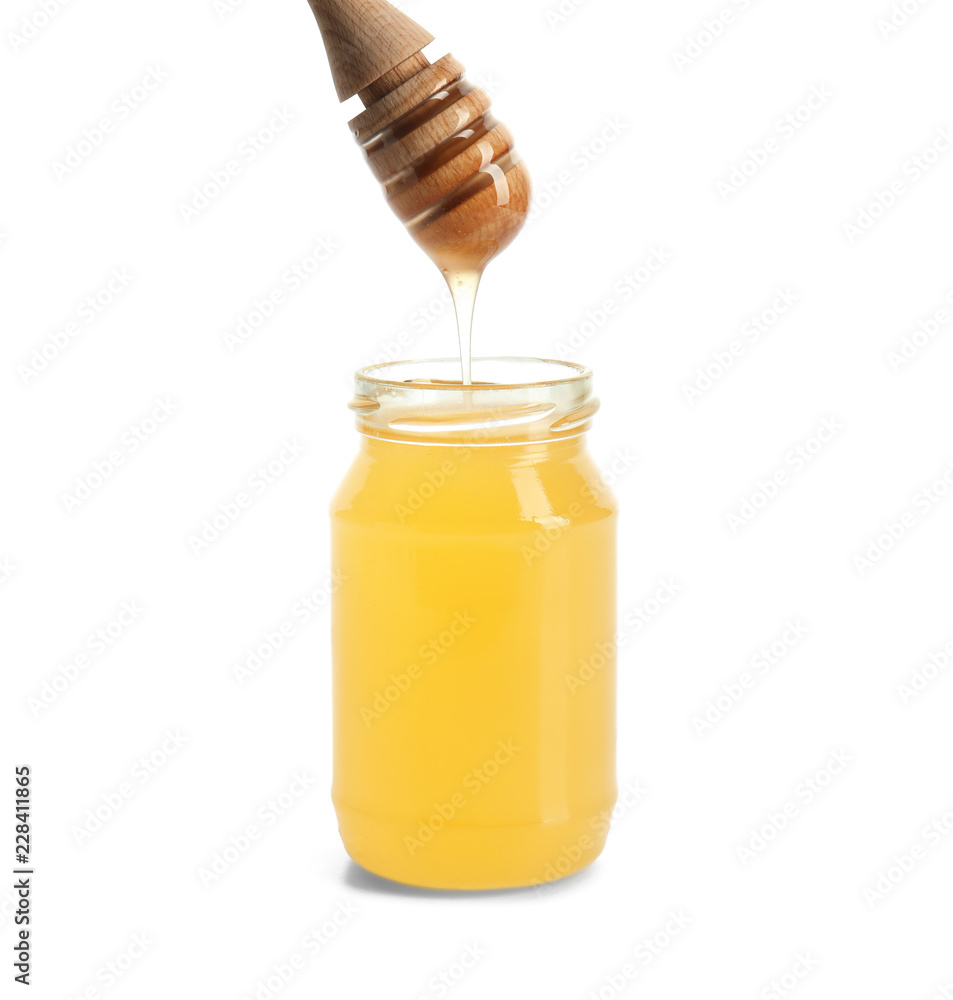 蜂蜜从勺子滴到白色背景的罐子里