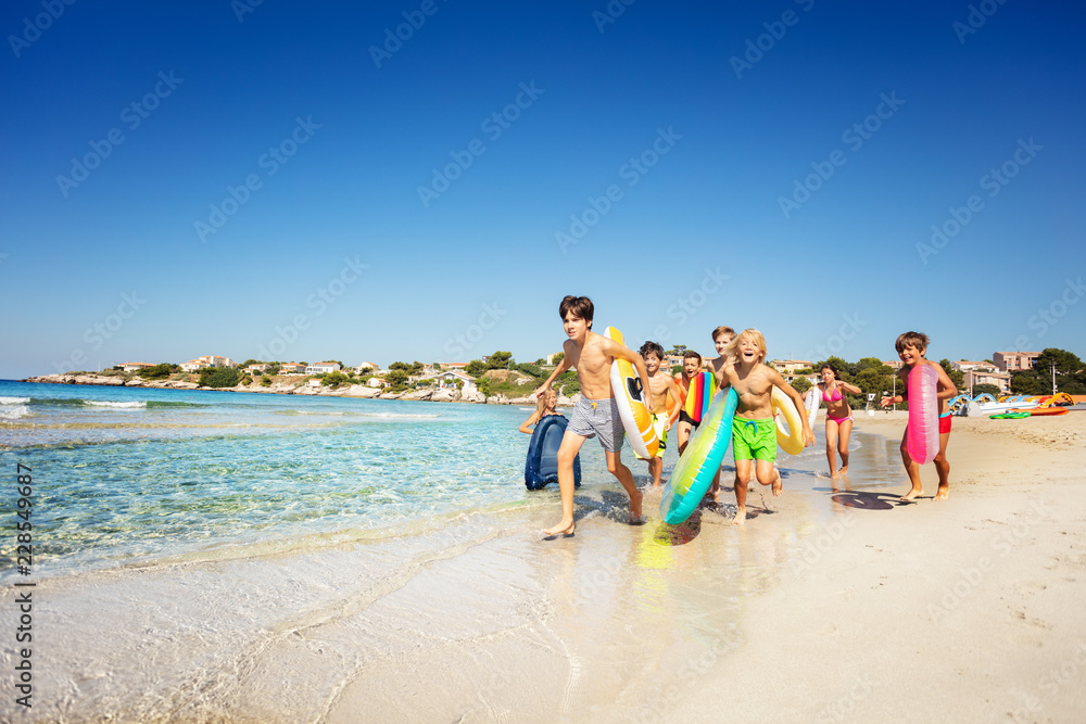 快乐的青少年在夏天沿着沙滩奔跑