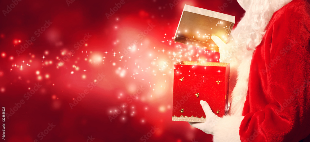 圣诞老人在闪亮的灯光背景下打开礼盒