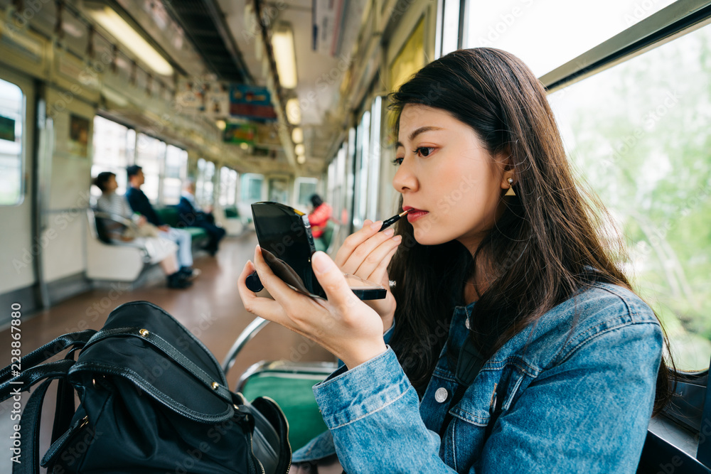 an elegant lady doing makeup on the subway