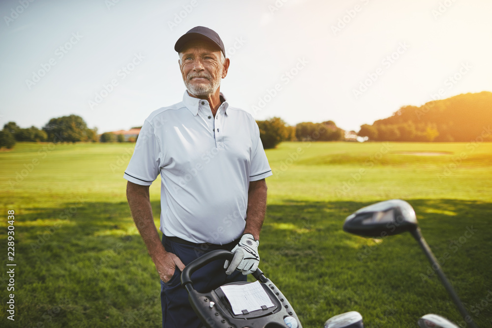 一位老人拿着球杆站在高尔夫球场上