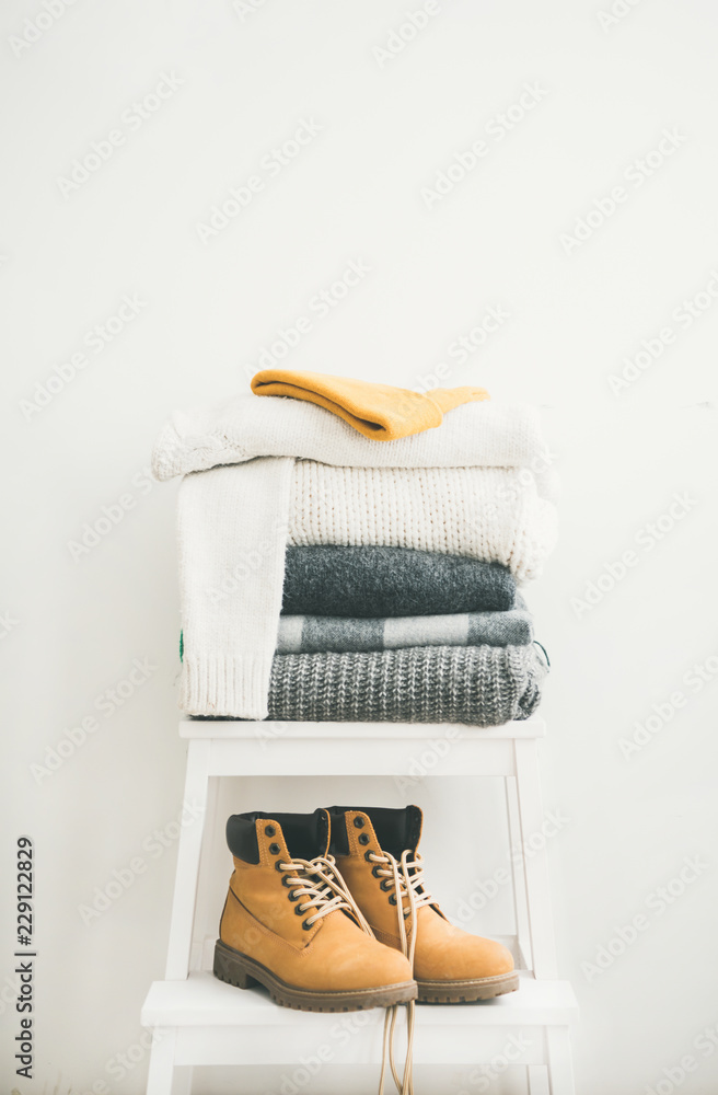 一堆保暖的灰色和白色毯子、围巾和羊毛衫、帽子和靴子，冬天用