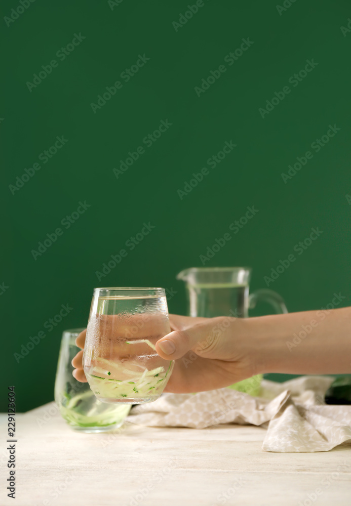 一位女士从餐桌上拿一杯新鲜的黄瓜水