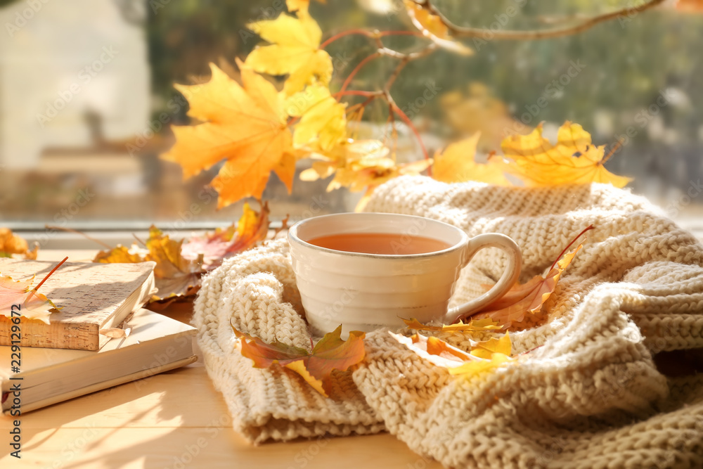 一杯芳香的茶，窗台上有温暖的格子和秋叶