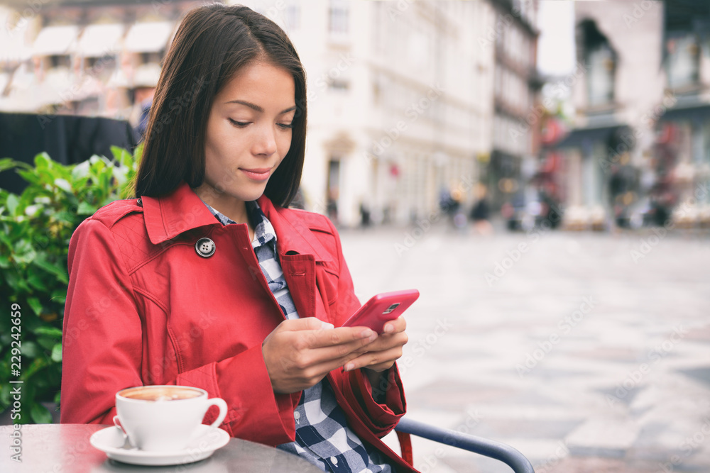 在欧洲城市的户外街道上用手机喝卡布奇诺咖啡的女咖啡馆