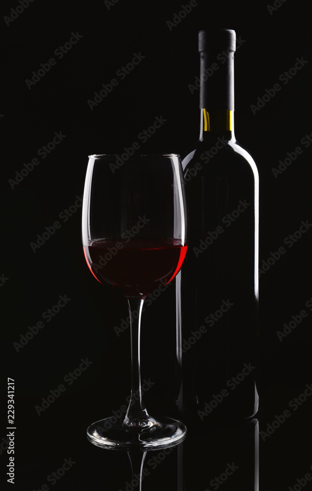 一瓶又一杯深色背景的红酒
