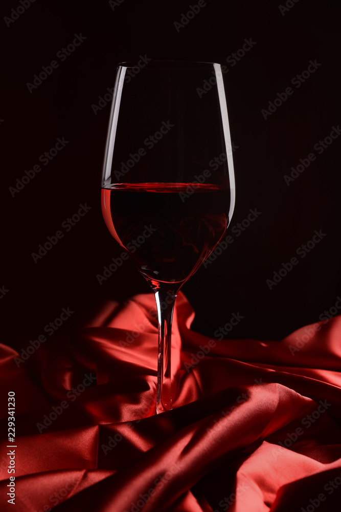 一杯深色背景上有光泽布的红酒