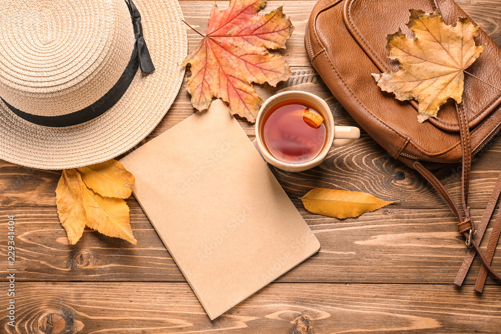 木质背景上的一杯芳香茶、帽子和秋叶组成
