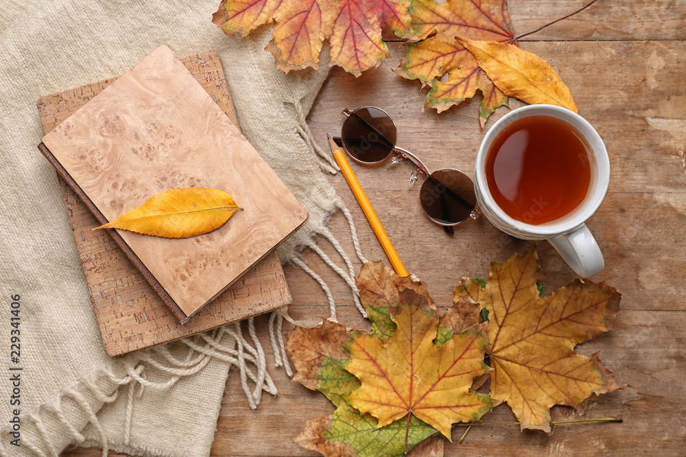 用一杯芳香的茶、温暖的格子、书籍和木底秋叶组成