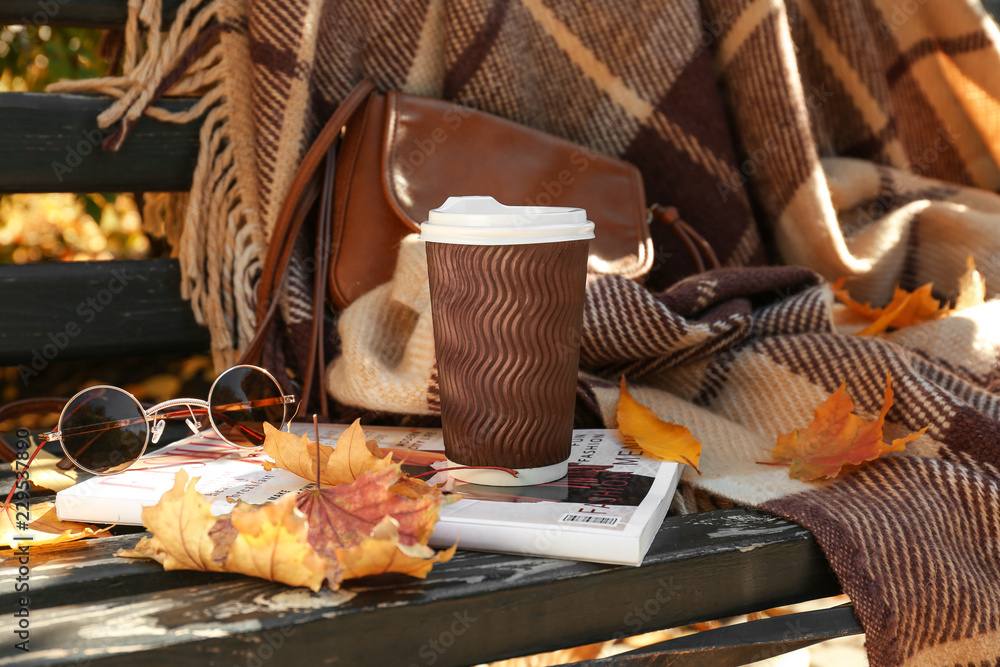 一杯热咖啡，木凳上有杂志和秋叶
