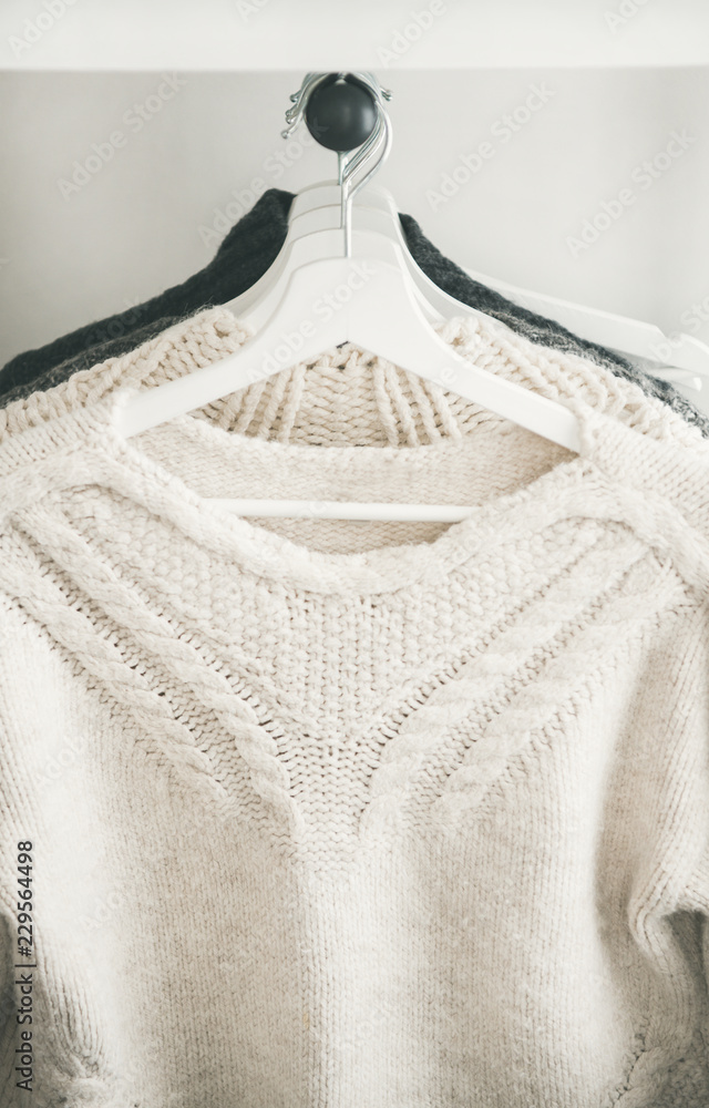 一排温暖的针织毛衣挂在衣架上，冬天或秋天寒冷的天气，特写。舒适的家