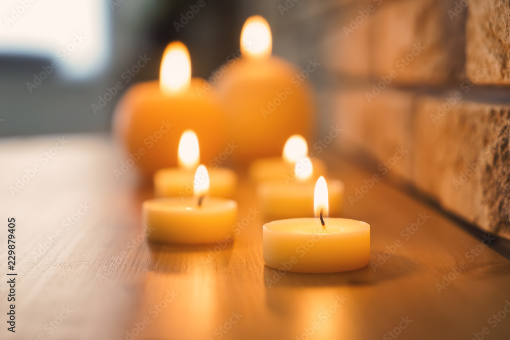 砖墙附近的木桌上燃烧着美丽的蜡烛