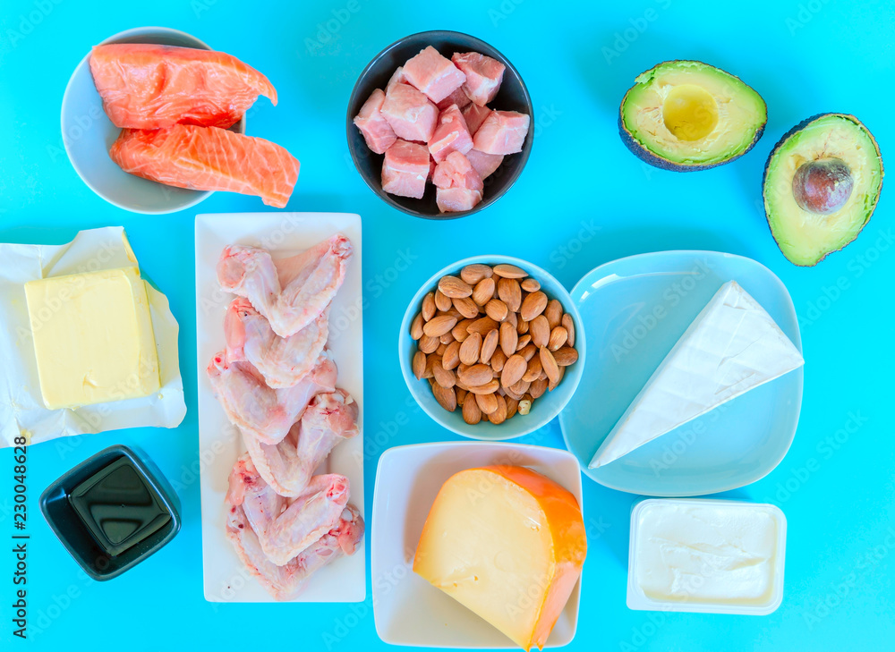 生酮减肥食品。低碳水化合物食物背景，蓝色ba上的鱼、肉、奶酪、坚果、油和黄油