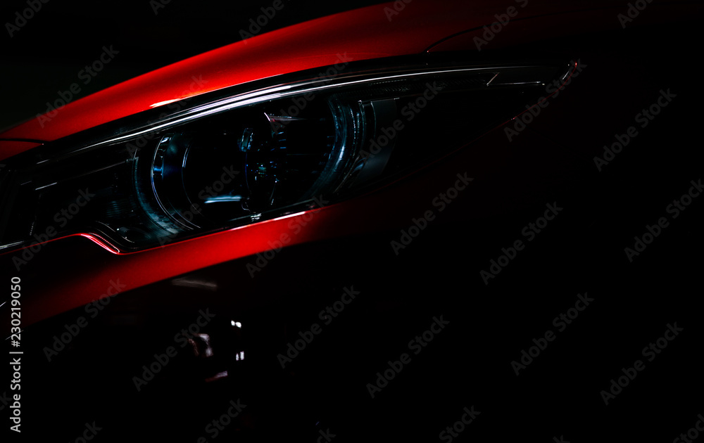 闪亮的红色豪华SUV紧凑型轿车的特写大灯。优雅的电动汽车技术和商务