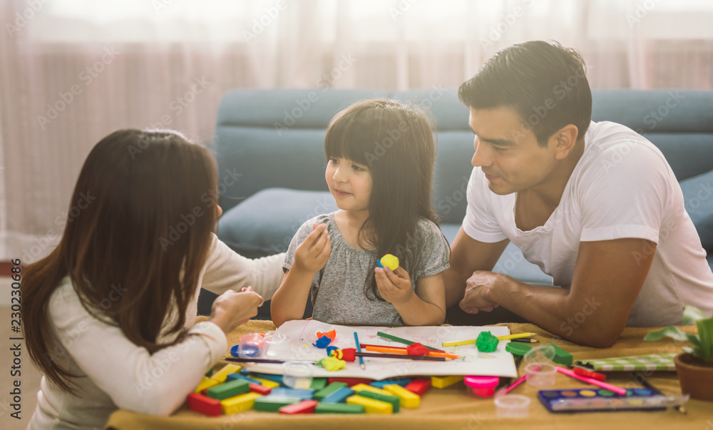 幸福家庭女儿的画像女孩正在学习与父母一起使用五颜六色的面团
