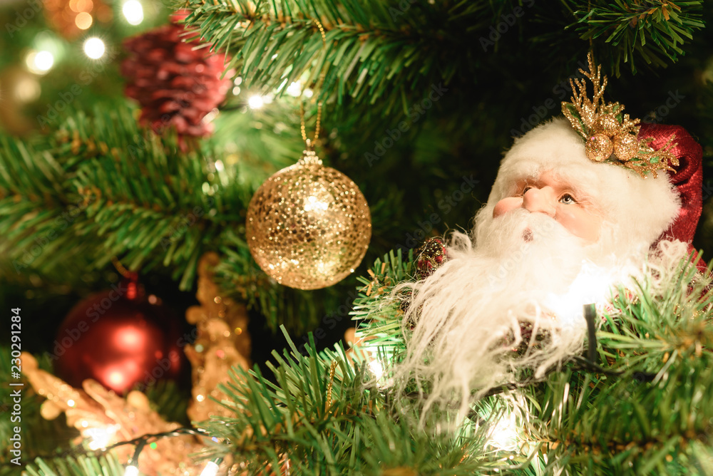 用圣诞老人玩偶、圣诞球和灯光装饰的圣诞树特写