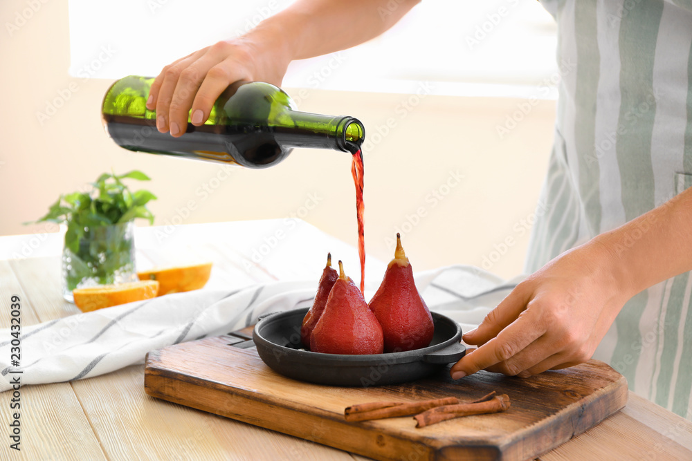 女人在厨房里把葡萄酒倒在装有甜梨的平底锅上