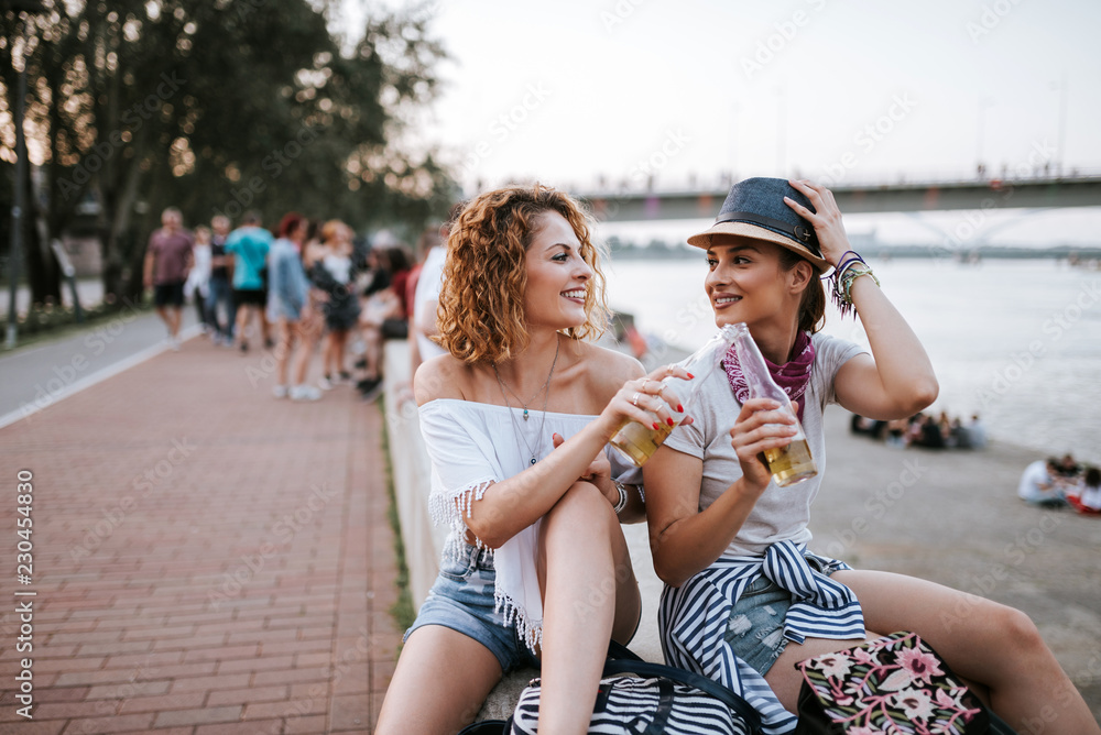 夏天很有趣。女孩们在城市的河边喝酒。