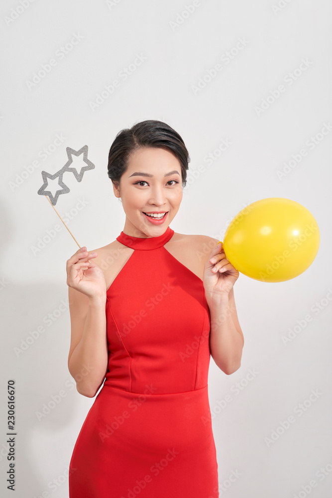 身穿红色连衣裙的美女拿着纸眼镜摆姿势，手里拿着白色背景下的气球