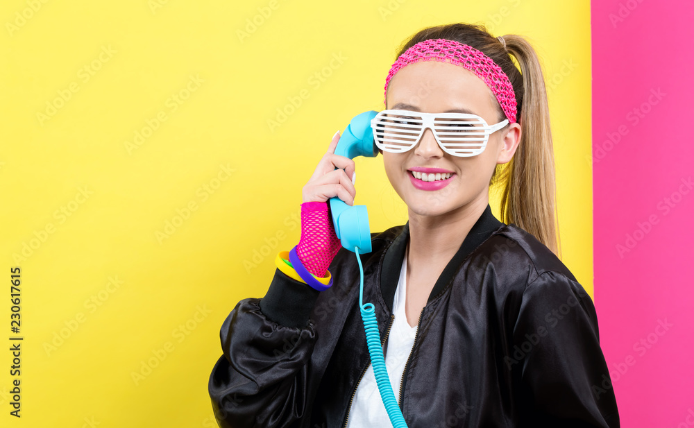 20世纪80年代时尚女性，黄色和粉色背景的老式手机