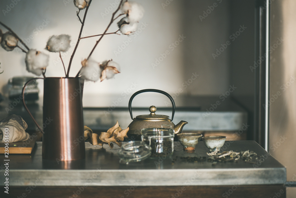 茶道。灰色混凝土上的金色铁茶壶和装满绿茶饮料的日本陶瓷杯