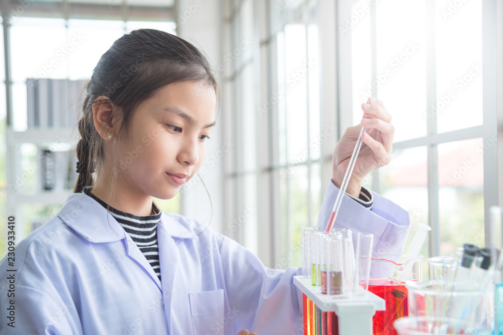 Young asian school girl doing experiment in chemistry classroom