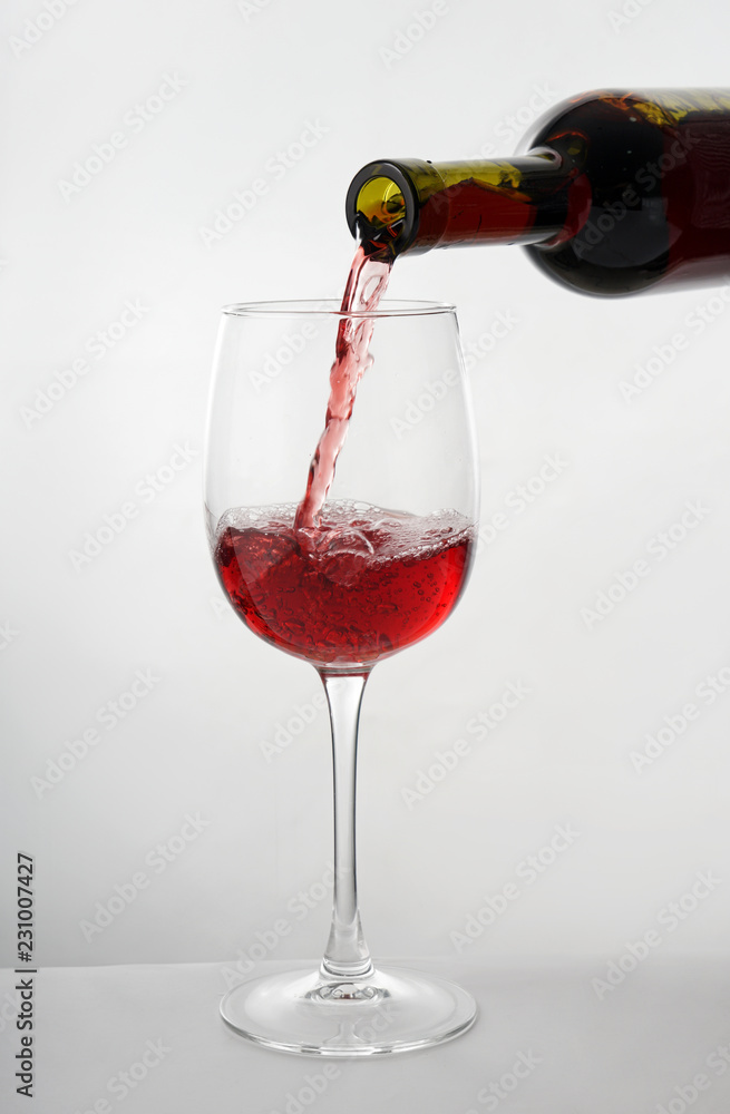 将美味的葡萄酒从瓶中倒入白底玻璃杯