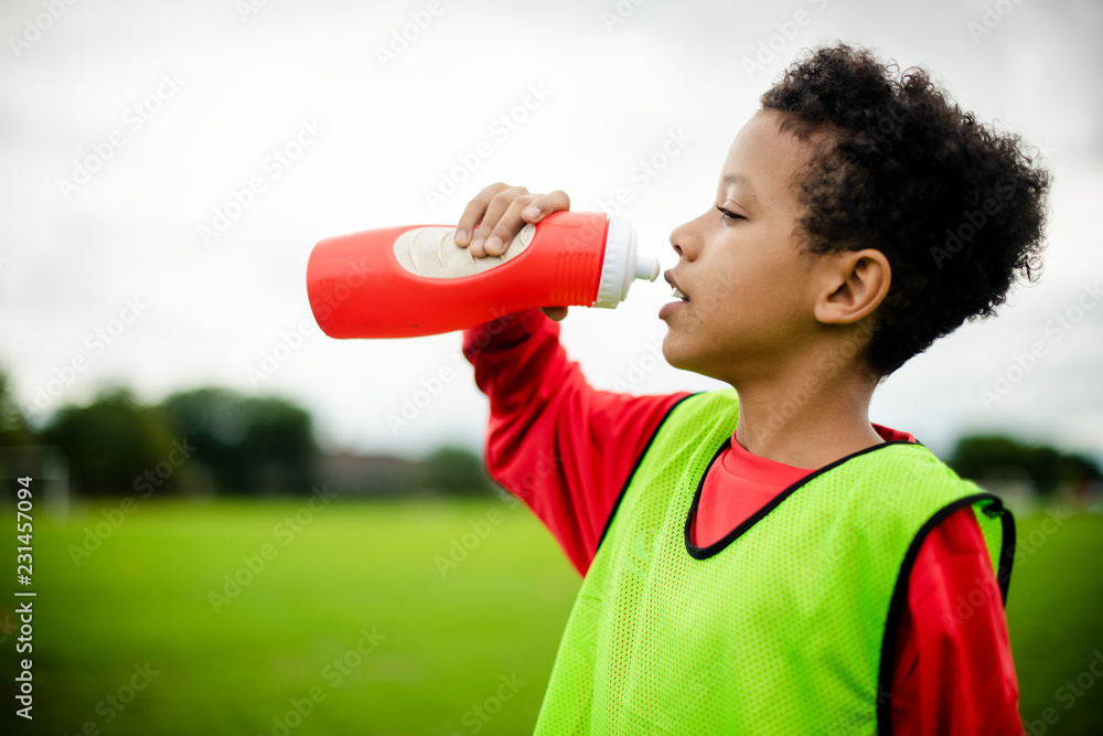 口渴的青少年足球运动员喝水