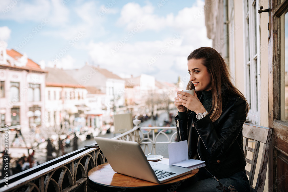 Cute girl drinking a cup of coffee on the balcony while studying.