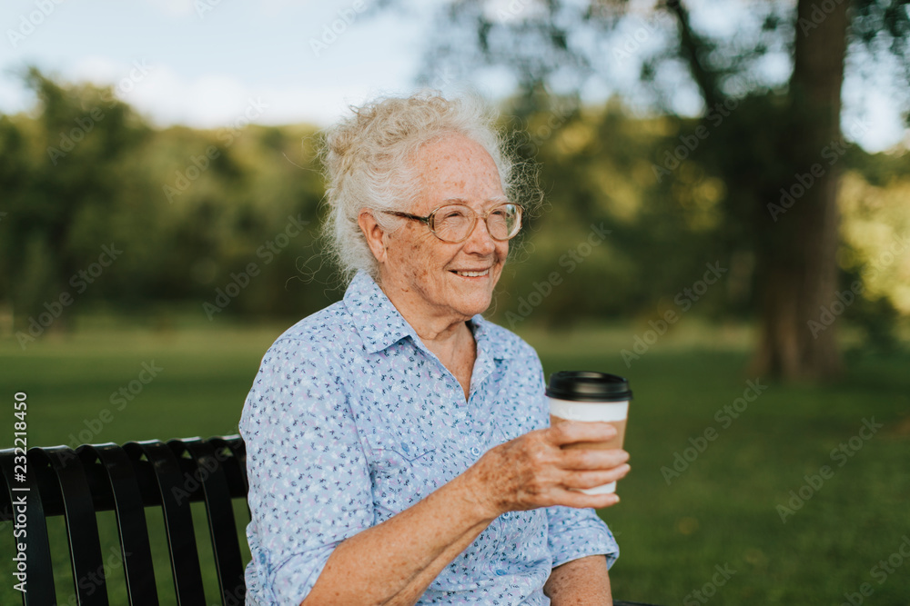 快乐的老年妇女在公园吃外卖咖啡