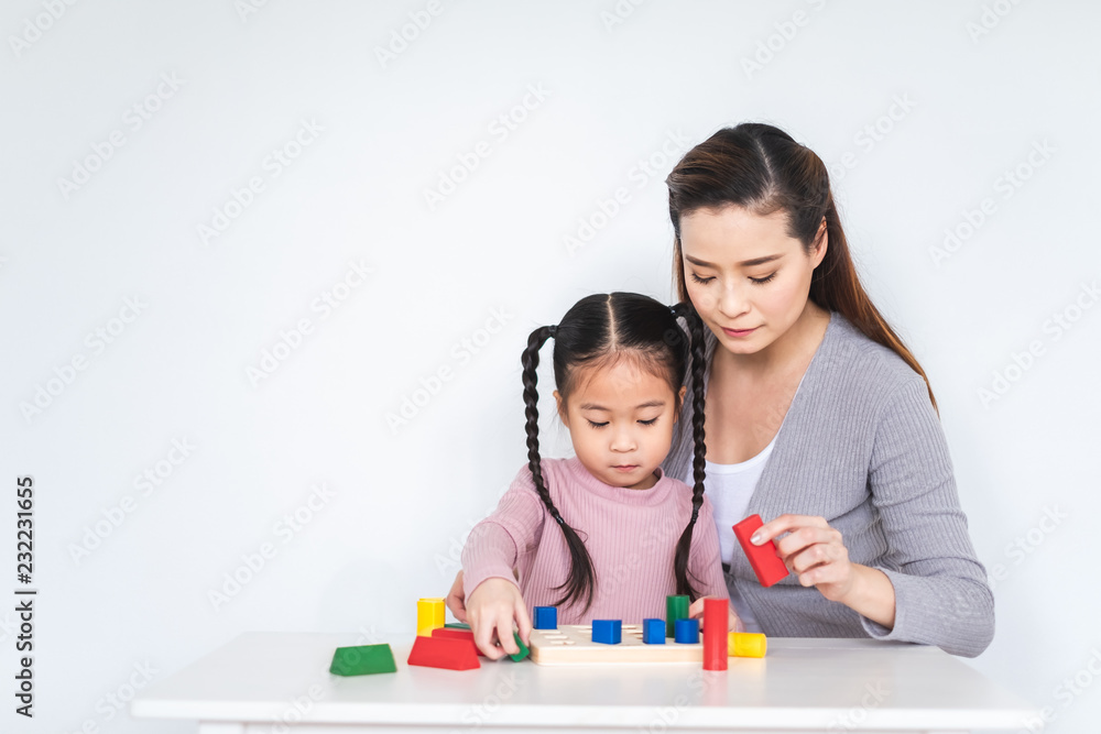 亚洲女孩女儿与母亲在白色背景下玩积木玩具，幸福的家庭理念