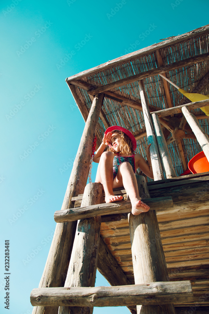 海滩上的小女孩。坐在救生塔前向前看