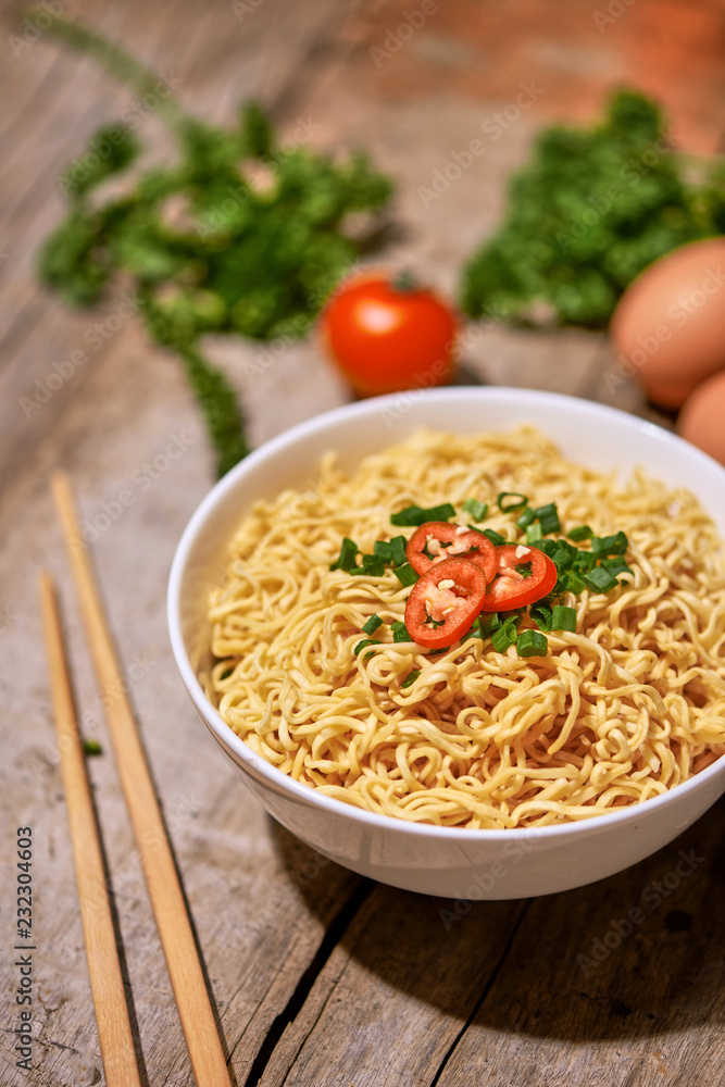 instant noodles in bowl with vegetable on wooden table.