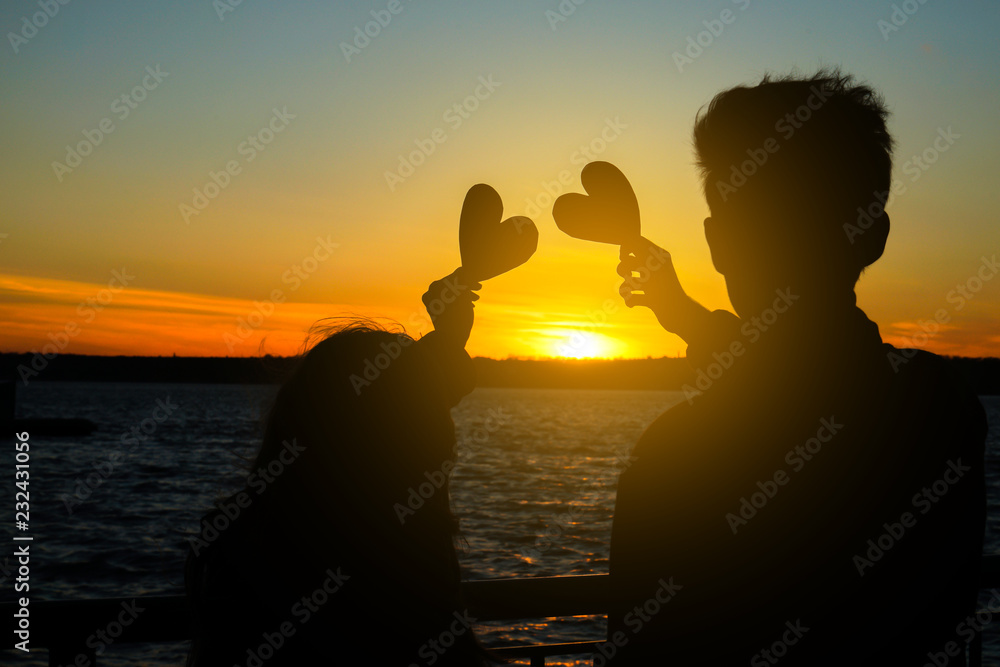日落时，河岸上有一对幸福的年轻夫妇，他们有装饰性的心