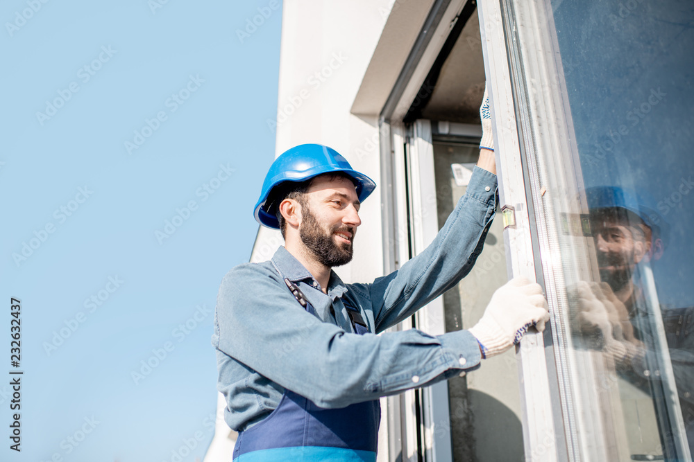 工人在统一安装的窗户中检查白色建筑立面的水平