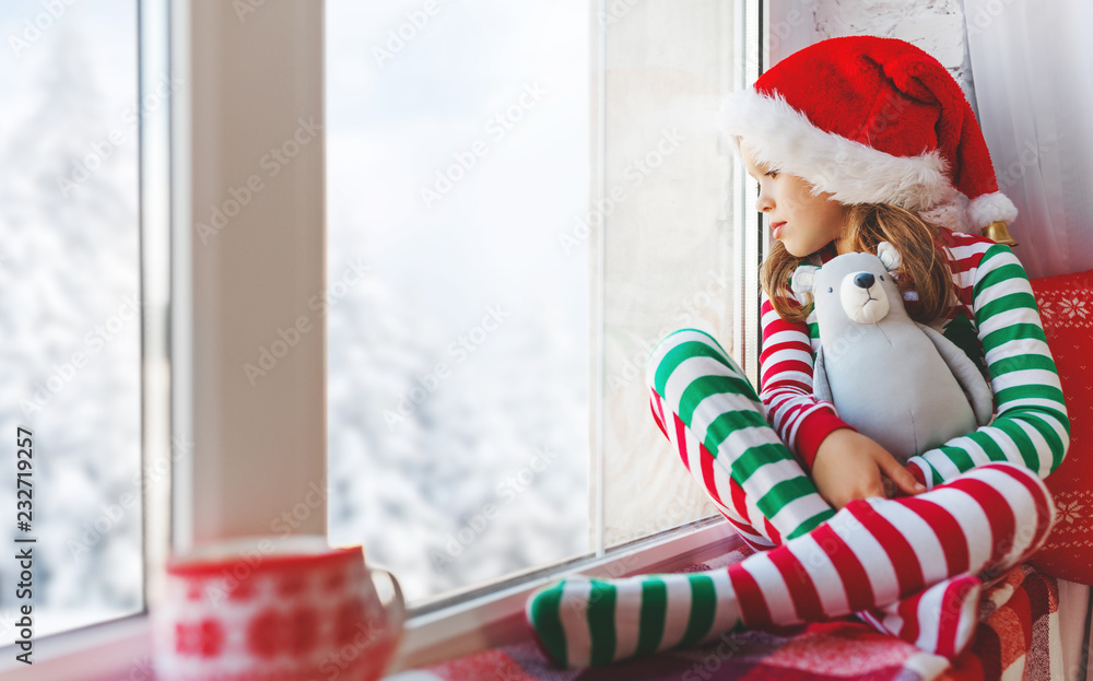child girl  is sad on Christmas morning by the window