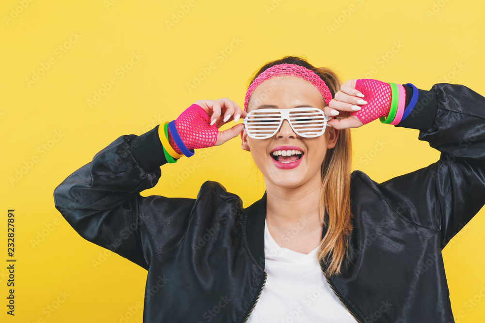20世纪80年代时尚的女人，黄色背景上戴着碎墨镜
